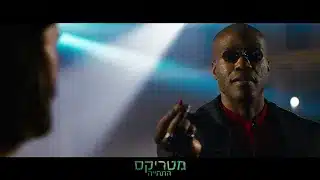 אדם המרכיב משקפי שמש מחזיק גלולה אדומה בתאורה עמומה.