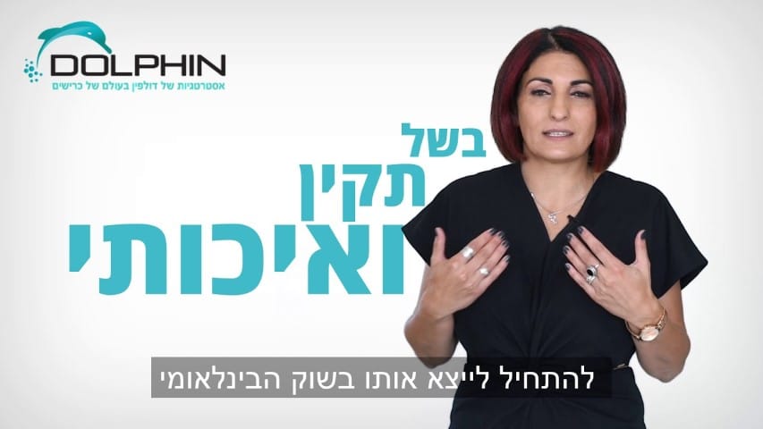 אדם בלבוש שחור מדבר מול תפאורה ממותגת דולפין עם טקסט בעברית.